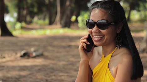mujer asiática con gafas de sol hablando por teléfono