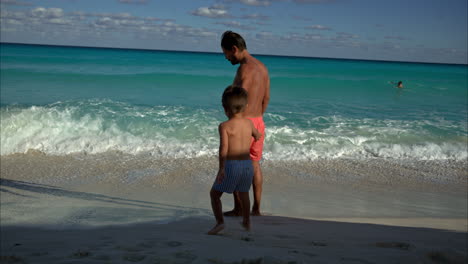 Zeitlupe-Eines-Mexikanischen-Lateinamerikanischen-Mannes-Mit-Bart,-Der-Seinen-Sohn-An-Einem-Strand-In-Cancun,-Mexiko,-Zum-Wasser-Einlädt