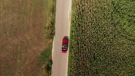 Vintage-Convertible-Car-Driving-Along-The-Road-By-The-Rural-Fields-At-Daytime-In-Zwolle,-Netherlands