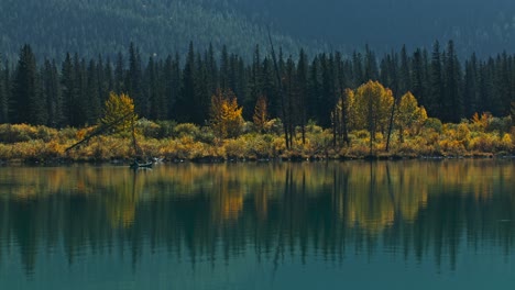 Canoe-on-lake-rowing-by-in-autumn-distant