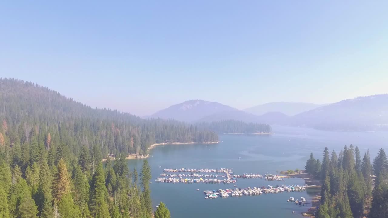 sobrevuelo aéreo ascendente de un pequeño puerto deportivo con barcos atracados en el lago shaver en las montañas de sierra nevada de california