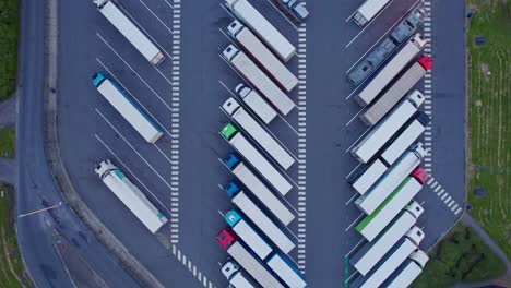 aerial, top-down moving shot of trucks parked on a parking lot near a highway in belgium