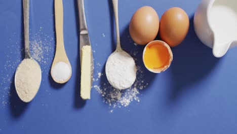 video of baking ingredients and spoons lying on blue surface