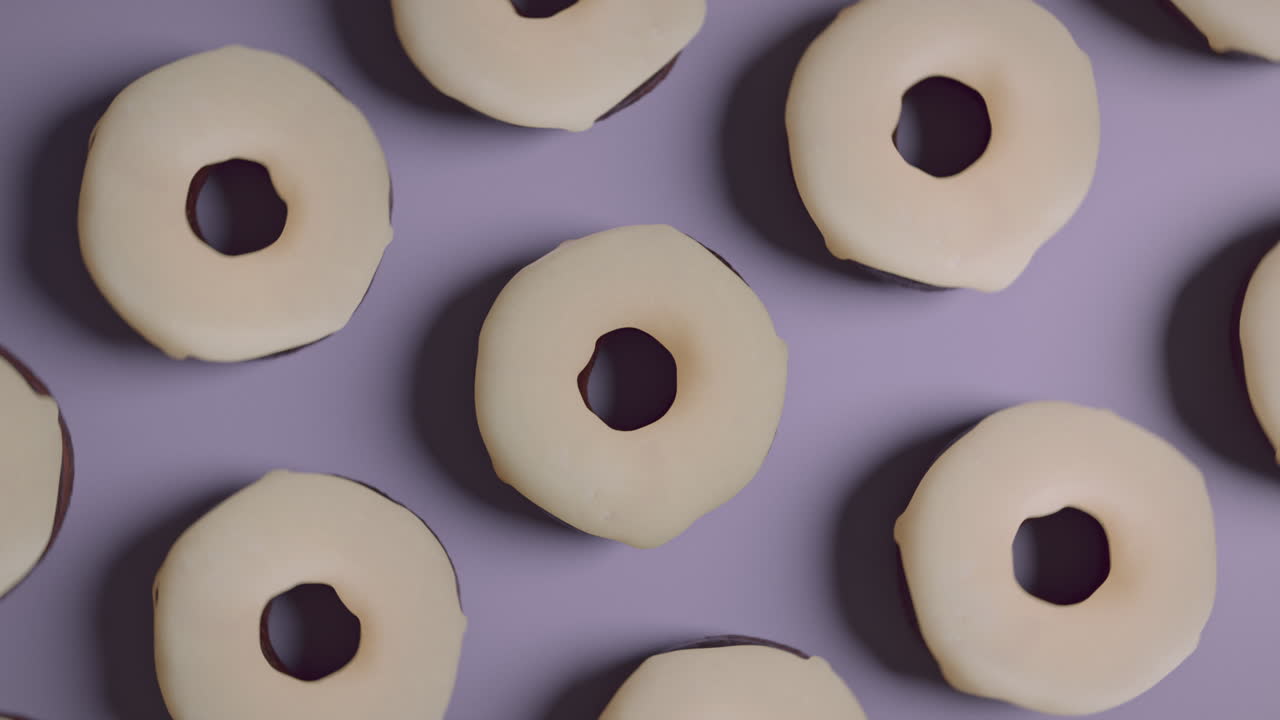 White glaze donuts on a light violet background