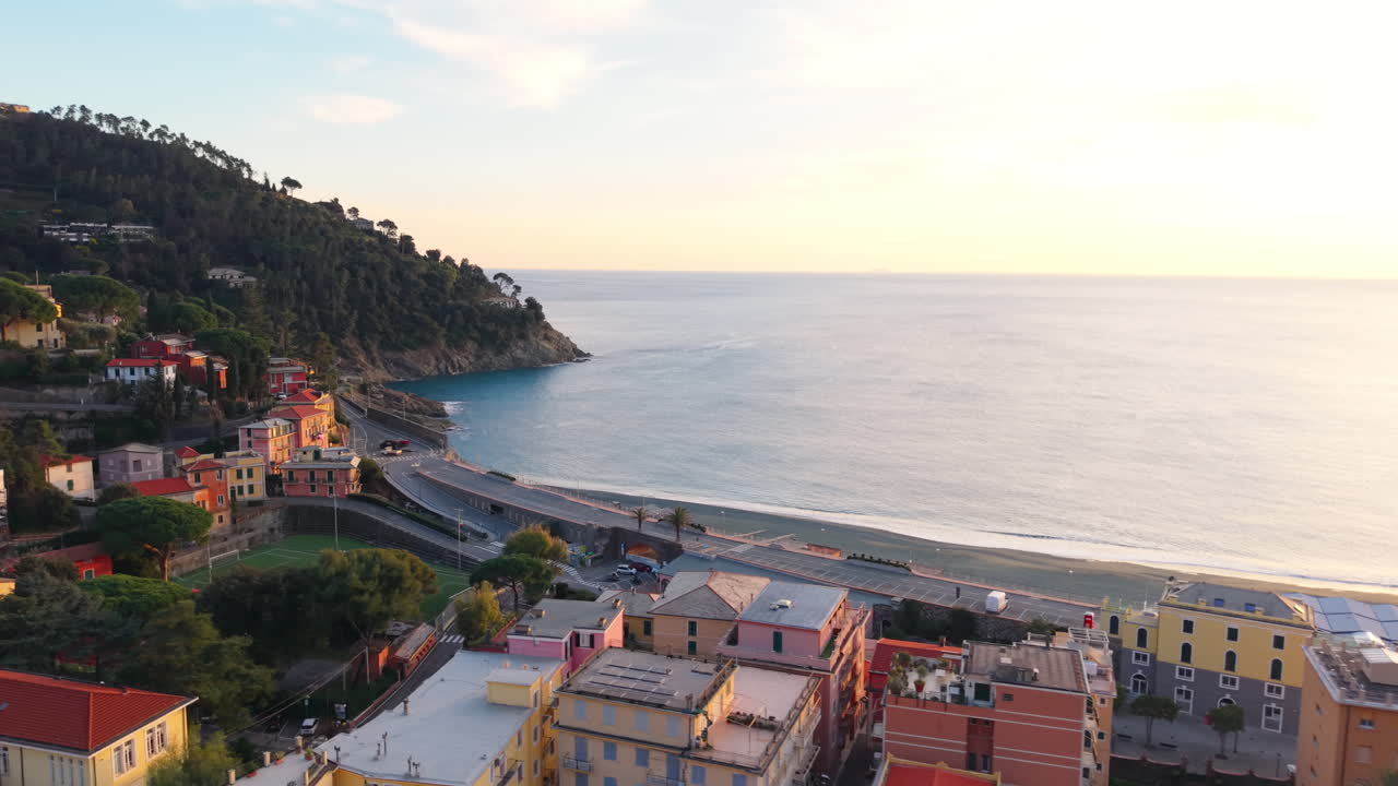 Ripresa a semicerchio da drone su Bonassola che rivela case colorate, la costa, la spiaggia e il mare al tramonto