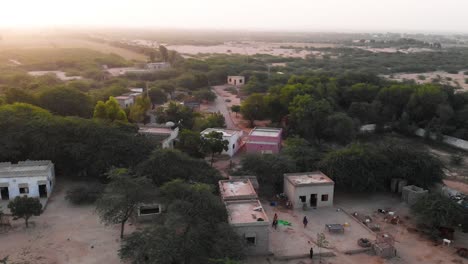 aerial orbit shot view of rural village in sindh with sunset on horizon