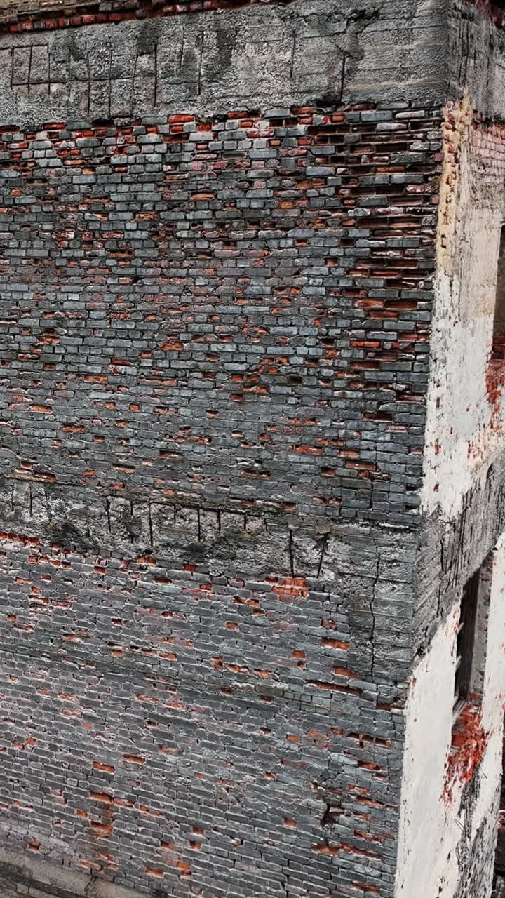 Decayed territory of an old factory. Warehouses that are no longer in use. Cityscape at the backdrop. Vertical video