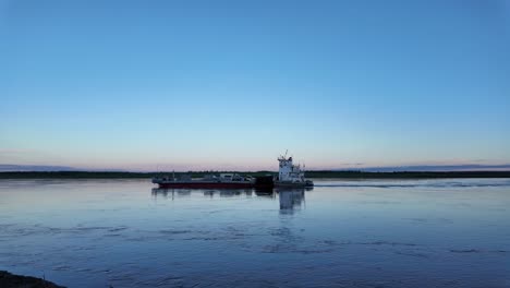 a ferry boat travels across a river at dusk in the russian far east