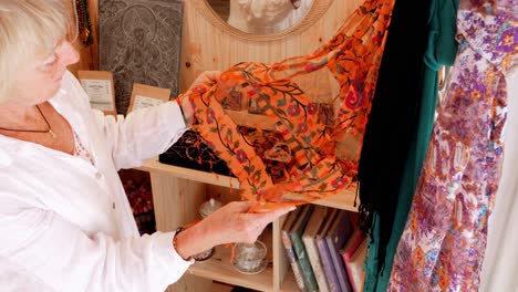 mujer rubia admirando una bufanda naranja en una boutique ecológica