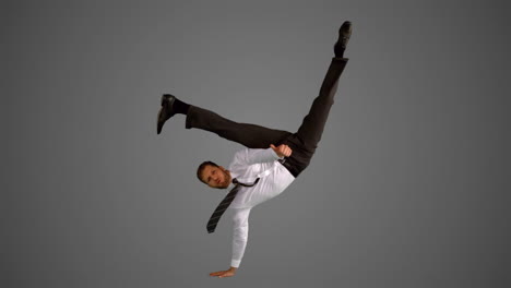 businessman doing one hand handstand on grey background