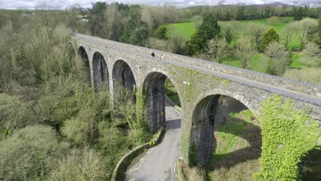 un viaducto con una vista ciclistas tomando un descanso para sumergirse en el cálido sol de primavera en waterford greenway