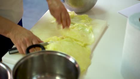 chef cutting thick part of cabbage leaves - stuffed cabbage roll preparation - close up