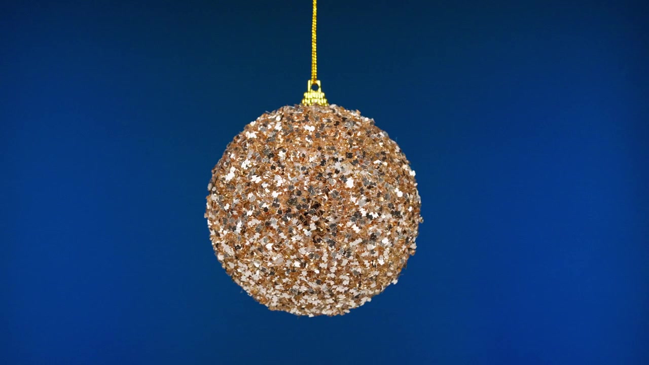 Funkelnder goldener und silberner Weihnachtsbaumschmuck vor blauem Hintergrund