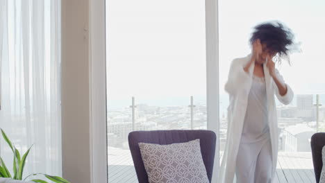 happy woman dancing at home wearing pajamas having fun celebrating lifestyle achievement enjoying happy dance in penthouse apartment