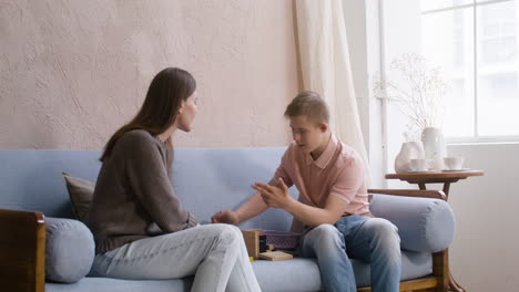 boy with down syndrome and his mother playing with wooden cubes on the sofa in the living room at home