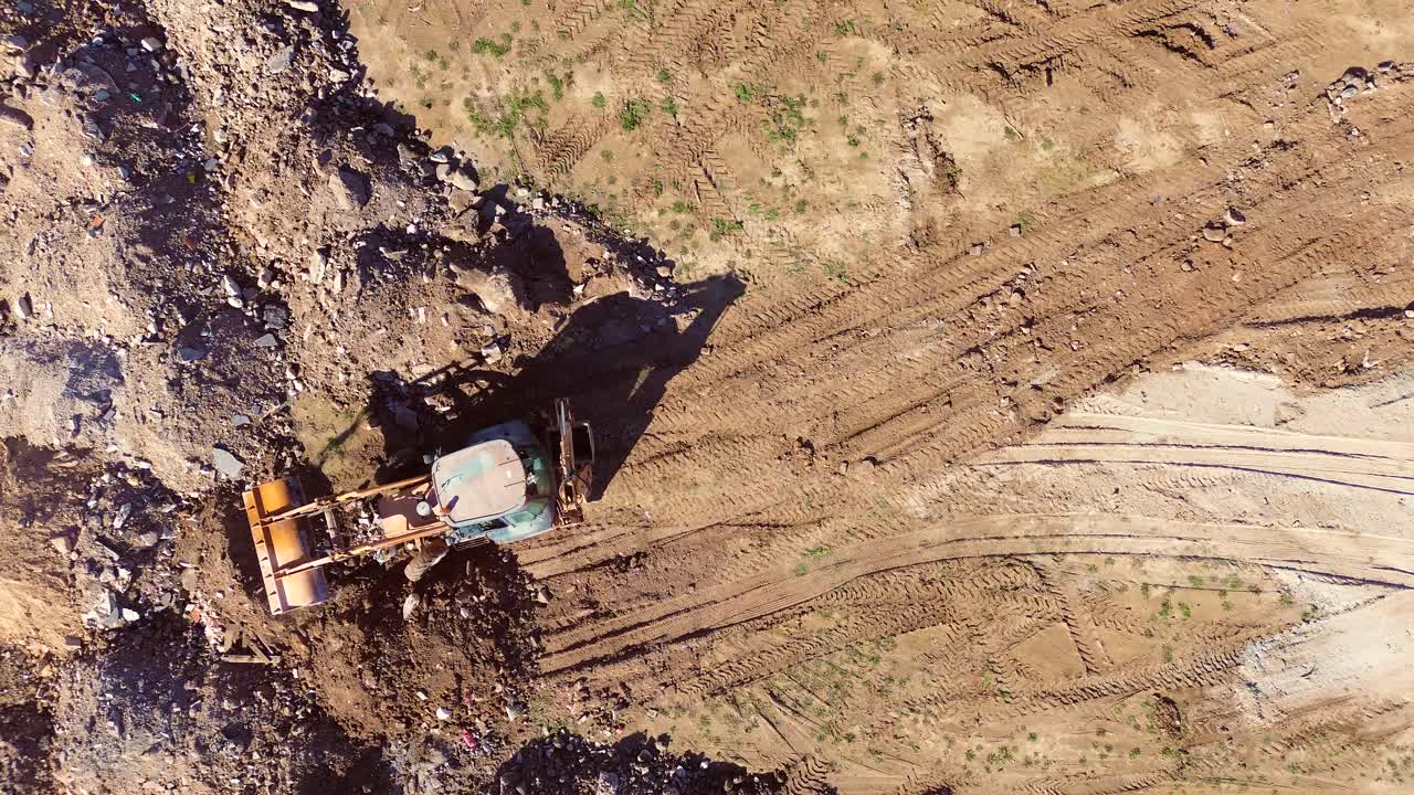 Luftfoto af en gravemaskine, der jævner og flytter jord på en byggeplads