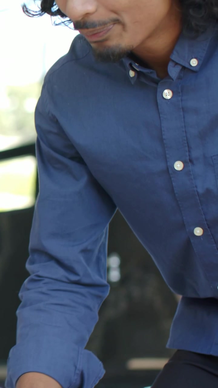Video verticale: Uomo con camicia blu scuro e orologio che si allunga verso una ciotola, chinandosi sul bancone vicino a un rubinetto della finestra.
