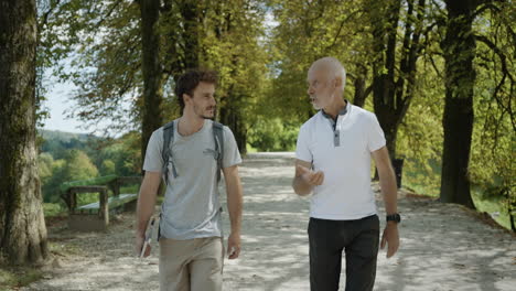 a young hiker is walking withe a older gentlemen throug the avenue of trees near ljubljana castle discusing hiking destinations