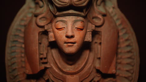 sculpture of goddes cover her head with a beast trophy illuminated by flames