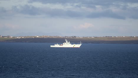 telephoto shot of a coastguard fisheries patrol vessel sailing over choppy water through the inlet of broadbay near stornoway, part of the outer hebrides of scotland