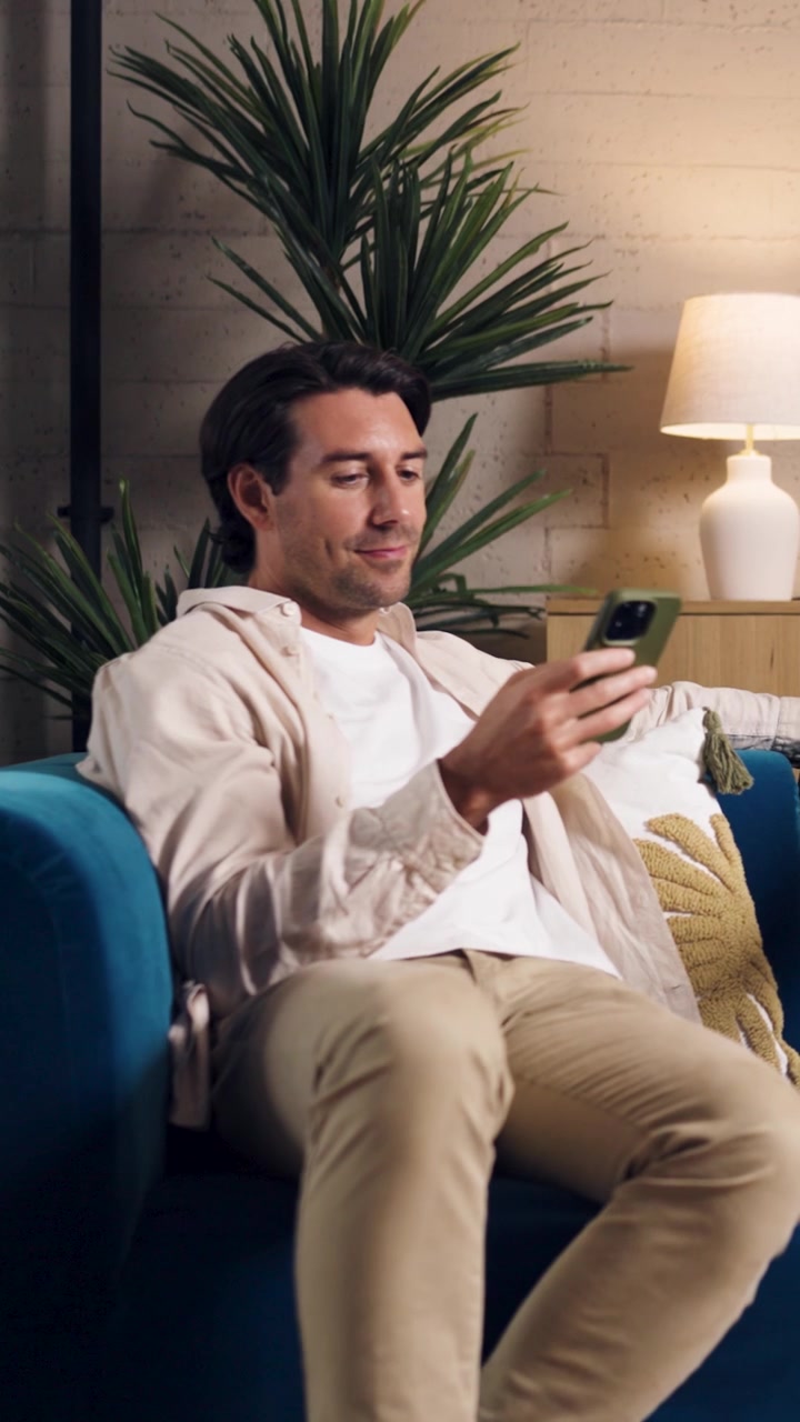 Uomo che si rilassa sul divano usando lo smartphone a casa