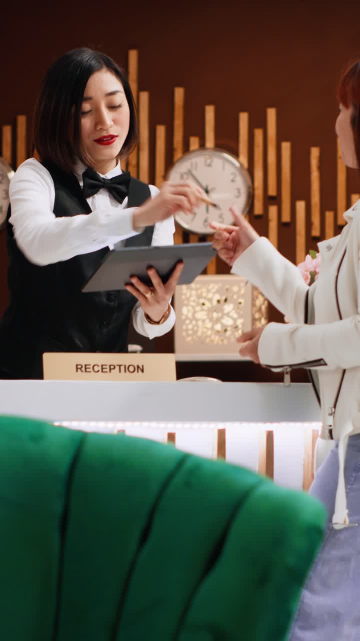 Video verticale: cliente firma un assegno su un tablet alla reception