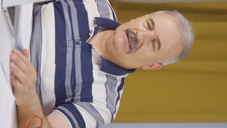 Vertical-video-of-Home-office-worker-old-man-looking-annoyed-at-camera.