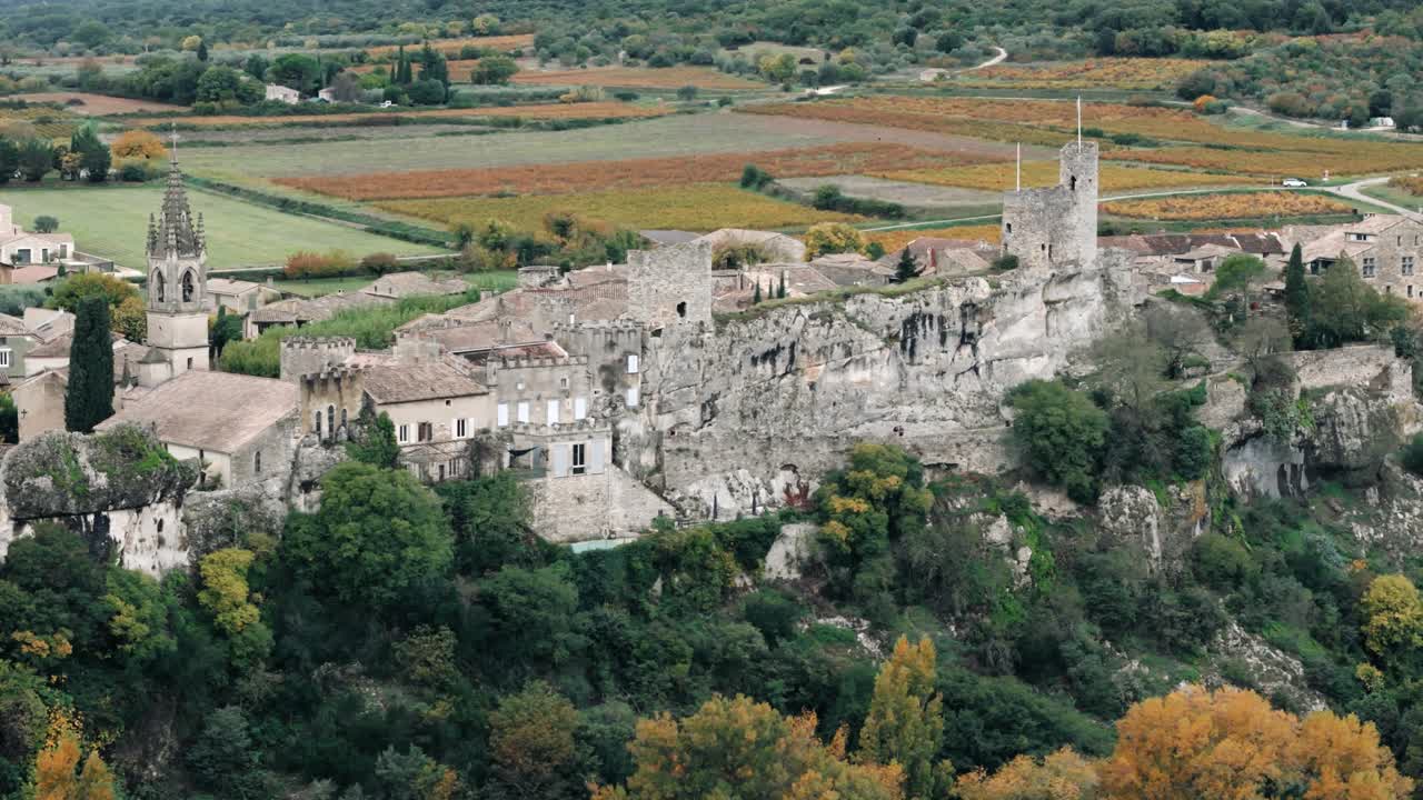 Borgo medievale su una scogliera in Provenza, sopra vigneti autunnali.