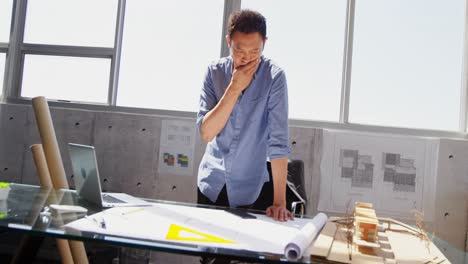 Front-view-of-Asian-male-architect-with-hand-on-chin-working-at-desk-in-office-4k