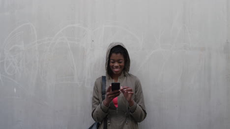 portrait young african american woman using smartphone texting browsing enjoying online communication on mobile phone wearing hood slow motion