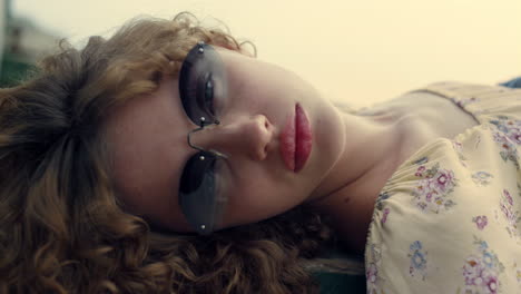 closeup girl opening eyes wearing sunglasses on nature. portrait curly woman.