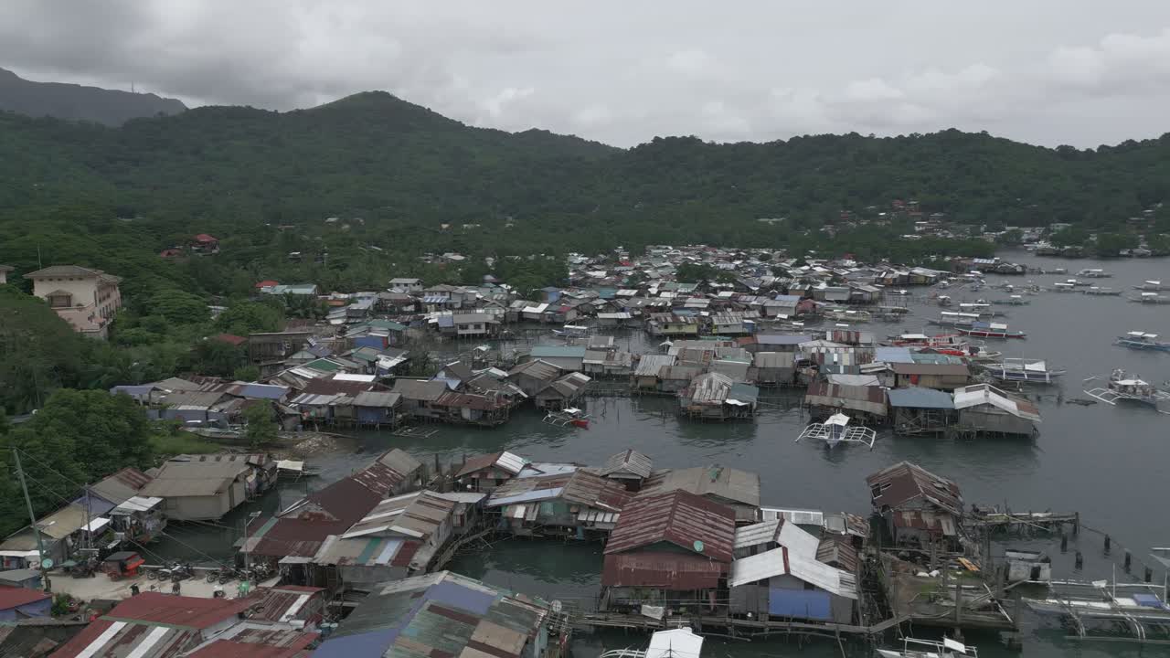 ภาพถ่ายทางอากาศมุมสูงแบบวงโคจร (Cinematic Orbit) ของบ้านยกพื้นสูงริมชายฝั่งในเมืองโคโรน ปาลาวัน สัญลักษณ์แห่งความยืดหยุ่นและการเอาชีวิตรอด
