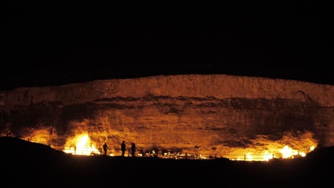 silhouettenfiguren durch brennenden krater