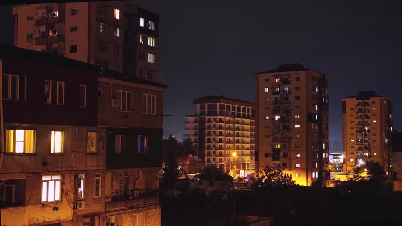 el time-lapse nocturno con una vista de las casas, las ventanas están iluminadas con luces.