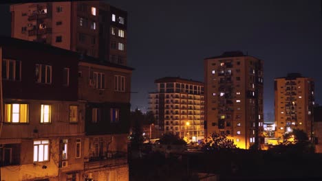 night timelapse with a view of the houses, the windows are lit with lights.