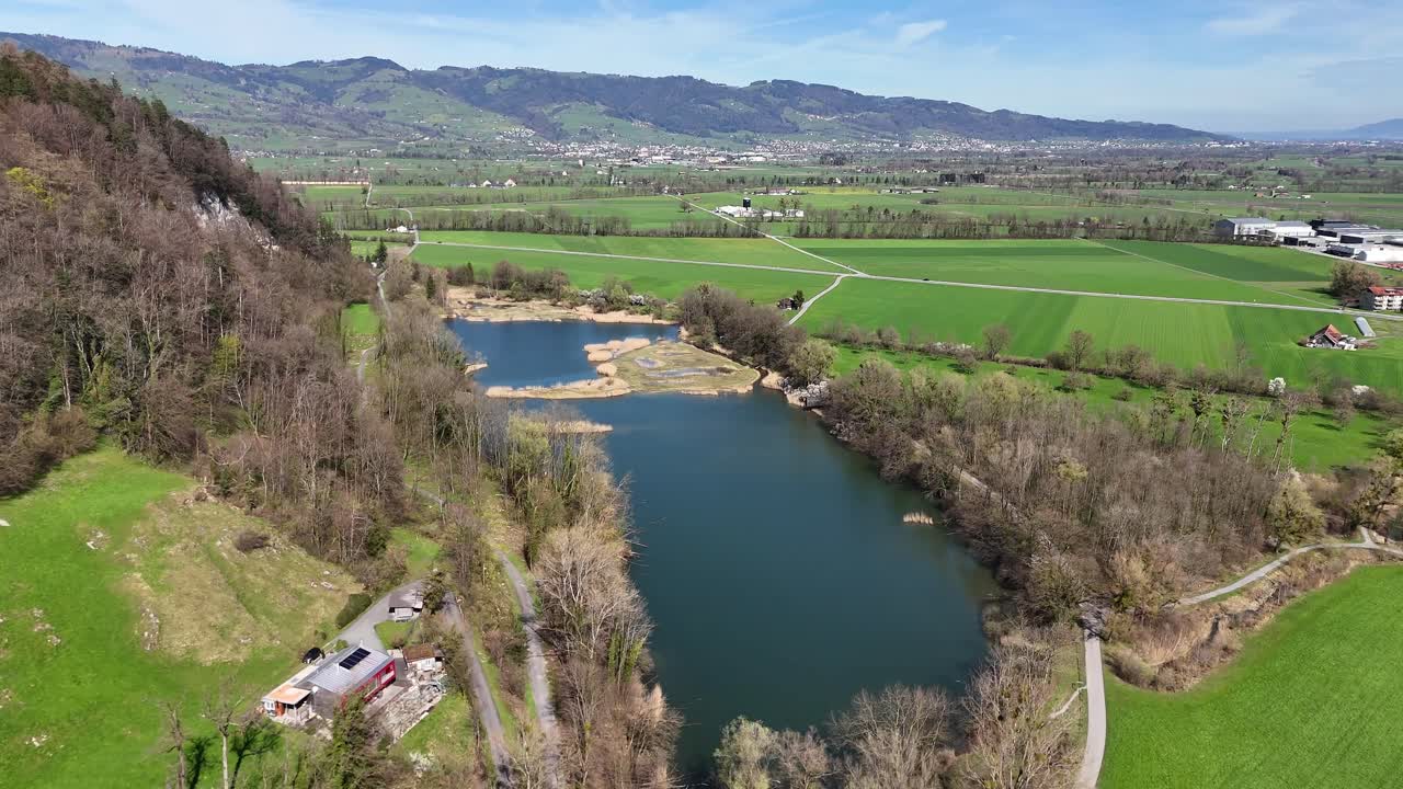 oberriet en suiza con un río serpenteante, campos exuberantes y colinas lejanas, bajo un cielo despejado, vista aérea
