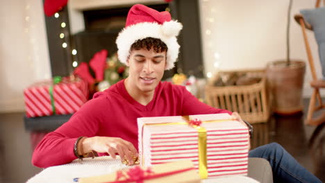 hombre biracial envolviendo un regalo de navidad en papel decorativo, cámara lenta