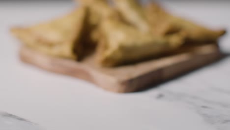 close up of samosas on wooden board on marble surface celebrating muslim festival of eid