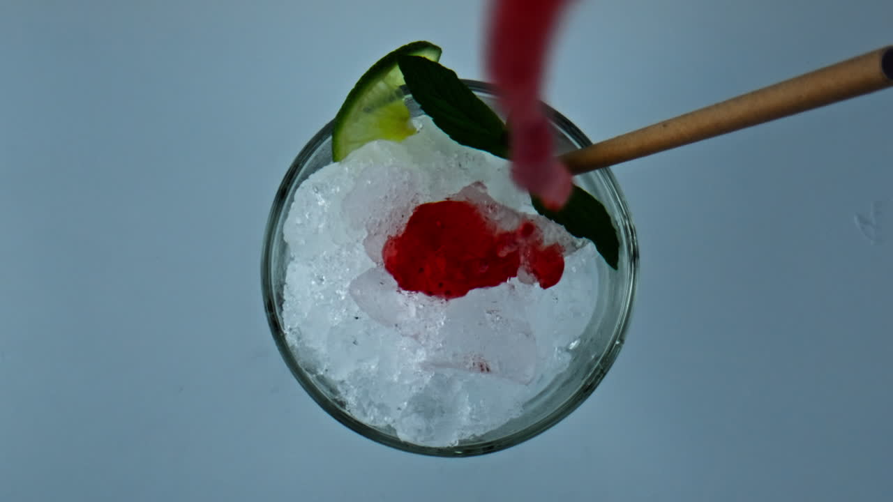 Pouring iced strawberry cocktail jam in glass closeup. Refreshing summer mojito