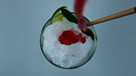 pouring iced strawberry cocktail jam in glass closeup. refreshing summer mojito