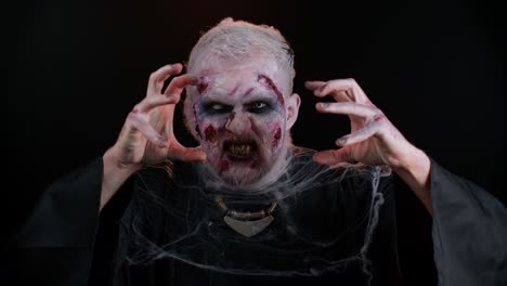 sinister man in costume of halloween crazy zombie with bloody wounded scars face trying to scare