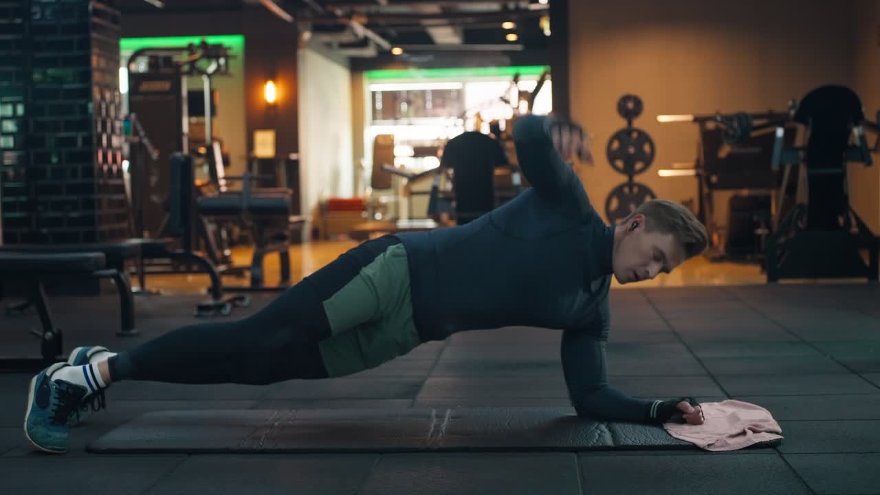 American athletic man training core strong abdominal oblique muscles doing Side Plank with Rotation, which builds strength and shoulder stability, improving hip flexibility