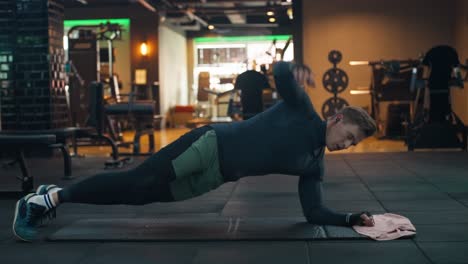 american athletic man training core strong abdominal oblique muscles doing side plank with rotation, which builds strength and shoulder stability, improving hip flexibility