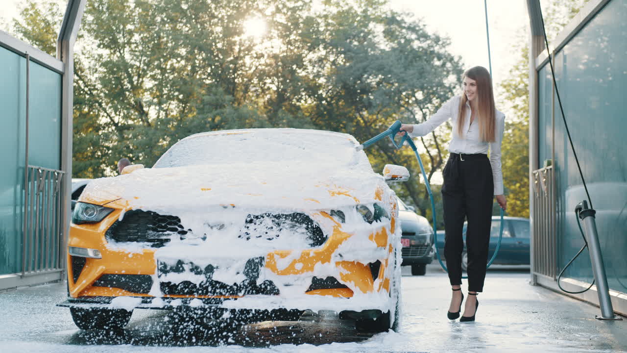 женщина моет желтую машину в автомойке самообслуживания