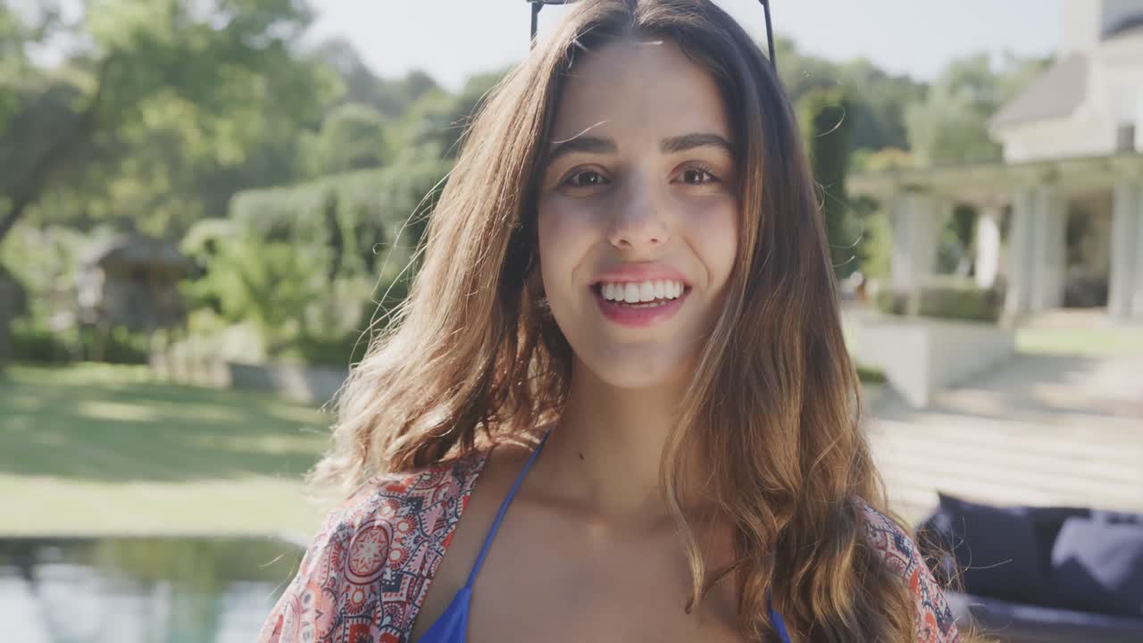 retrato de una feliz mujer biracial con gafas de sol en el jardín en un día soleado