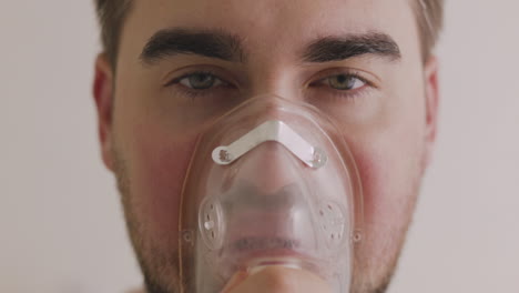 close up of a sick man breathing through oxygen mask and looking at camera