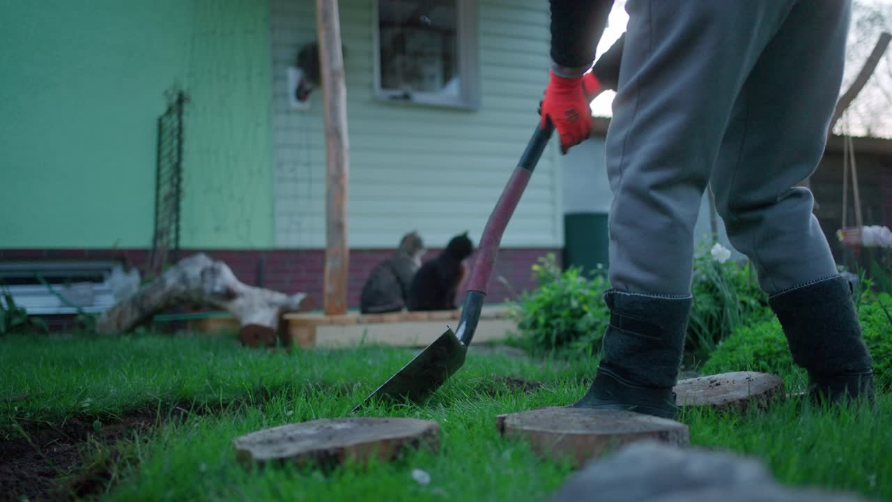 imagen de cultivo de una persona con una pala de jardinería en el césped del patio trasero durante la puesta de sol