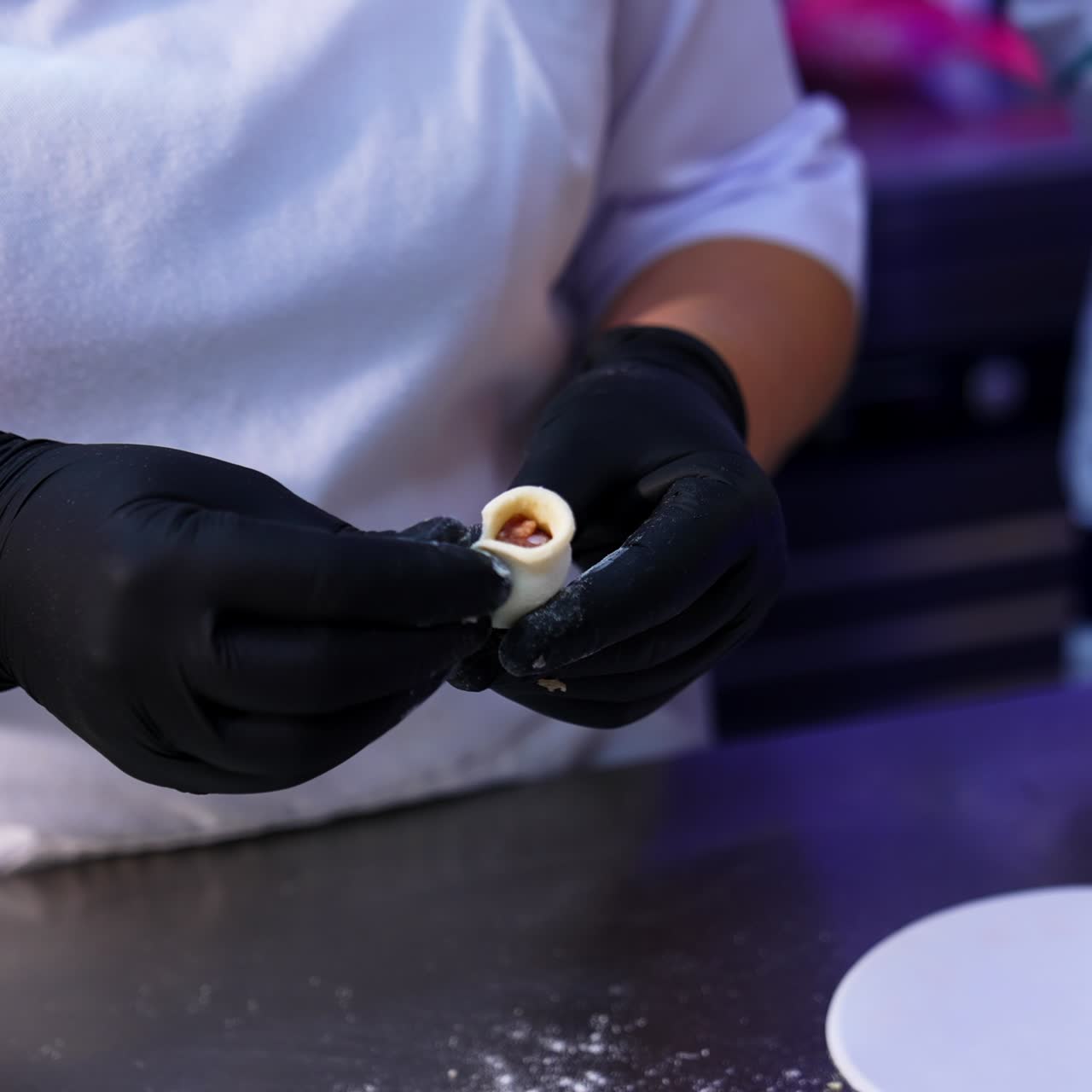 Gloved hands of a cook make the little dumplings. Two people making ravioli with meat at modern food factory