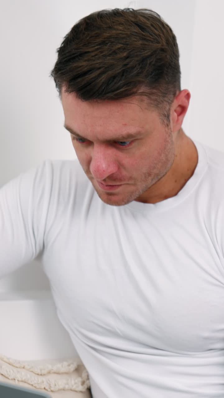 Caucasian male wearing white shirt opens his laptop. Working from home remote from office. Vertical video