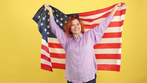 happy woman proudly displaying the american flag on a yellow background